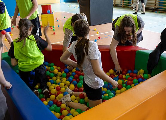 uczniowie w sali gimnastycznej  grają w paintballa