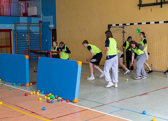 uczniowie w sali gimnastycznej  grają w paintballa