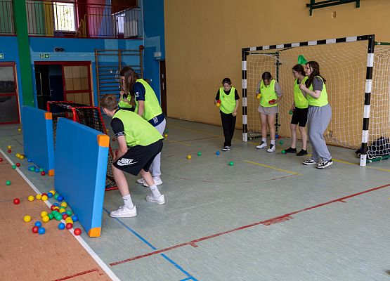 uczniowie w sali gimnastycznej  grają w paintballa