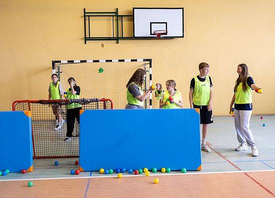 uczniowie w sali gimnastycznej  grają w paintballa