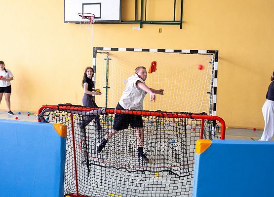 uczniowie w sali gimnastycznej  grają w paintballa