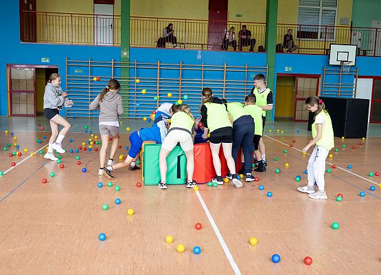 uczniowie w sali gimnastycznej  grają w paintballa