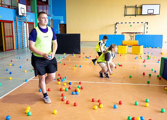 uczniowie w sali gimnastycznej  grają w paintballa