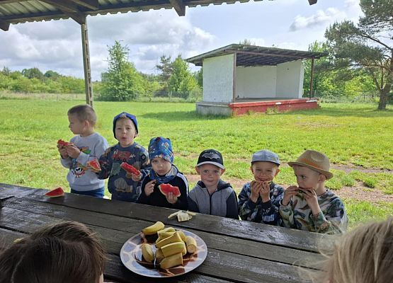 dzieci siedzą przy stoliku i jedzą