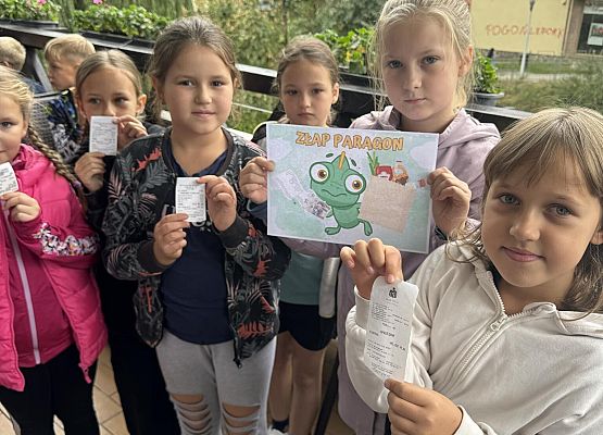 dzieci prezentują plakat informacyjny i paragony