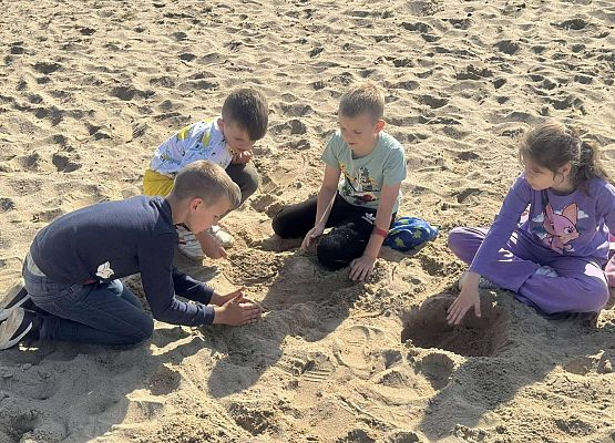 uczniowie bawią się piaskiem