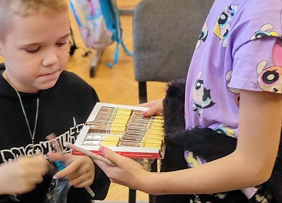 uczennica częstuje chłopców czekoladkami