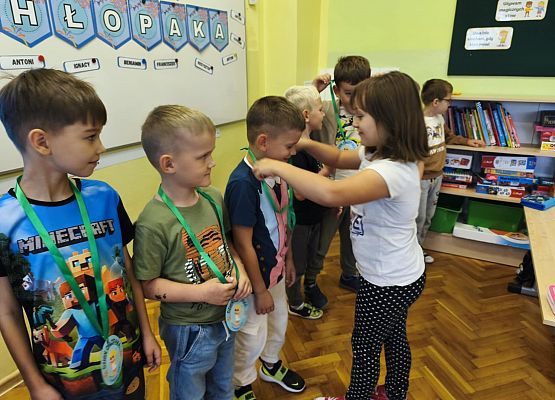 dziewczynka wręcza medale chłopcom