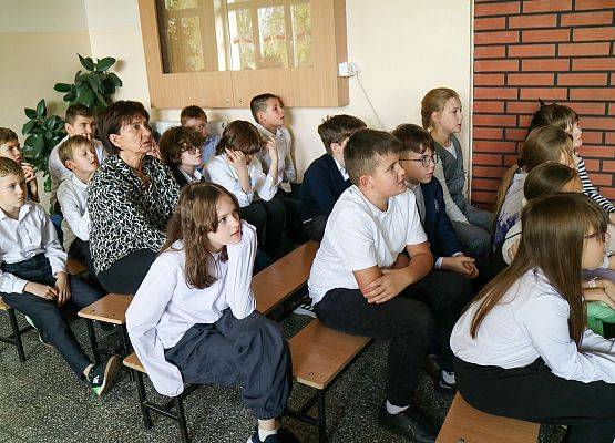 uczniowie siedzą na ławeczkach