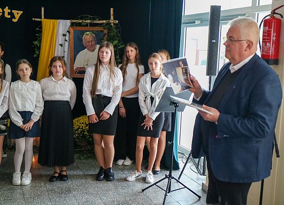 diakon rozdaje obrazki uczniom