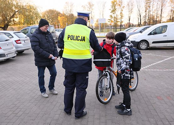 policjant rozdaje dzieciom szkolne worki