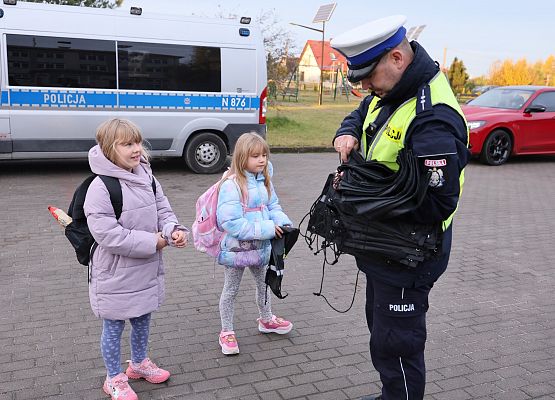 policjant rozdaje szkolne woreczki