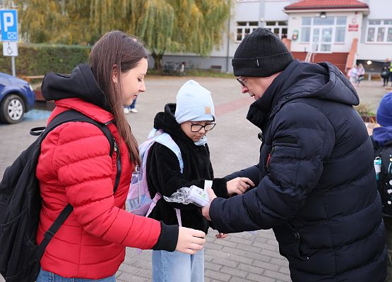 dyrektor zakłada dzieciom opaski odblaskowe