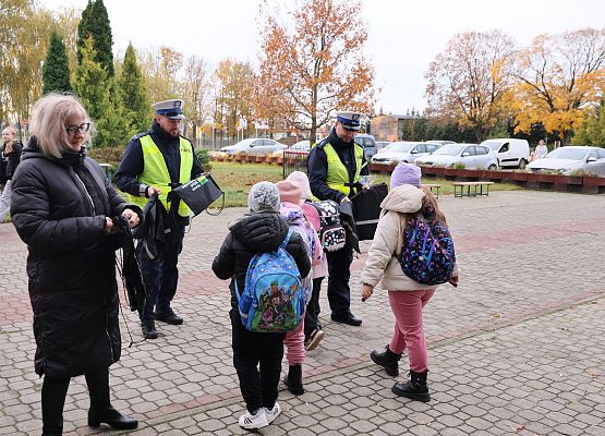 wicedyrektor policjanci rozdają dzieciom materiały odblaskowe