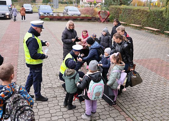 wicedyrektor i policjanci rozdają dzieciom materiały odblaskowe