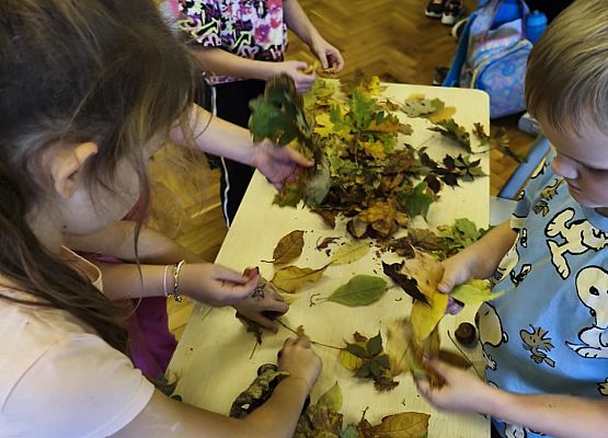 uczniowie wykonują prace plastyczne z jesiennych liści