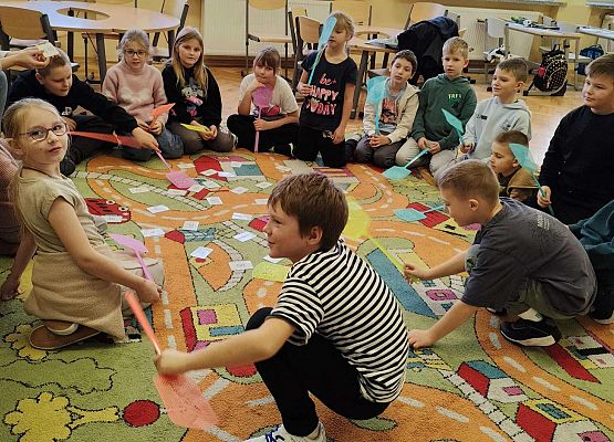 dzieci wykonując zadania bawią się na dywanie