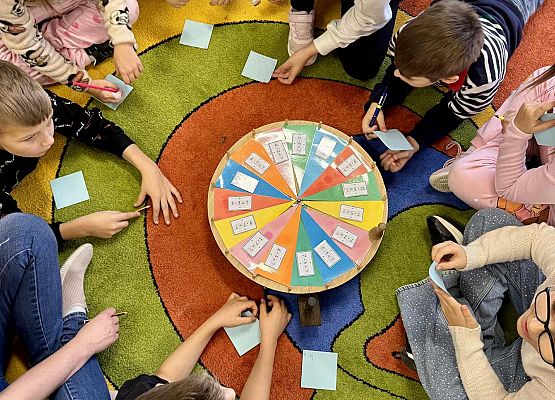 dzieci wykonując zadania bawią się na dywanie