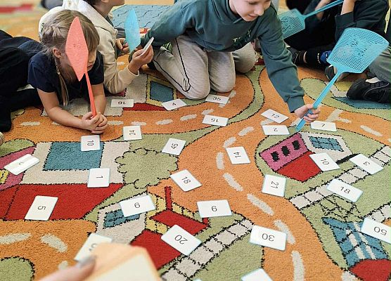 dzieci wykonując zadania bawią się na dywanie