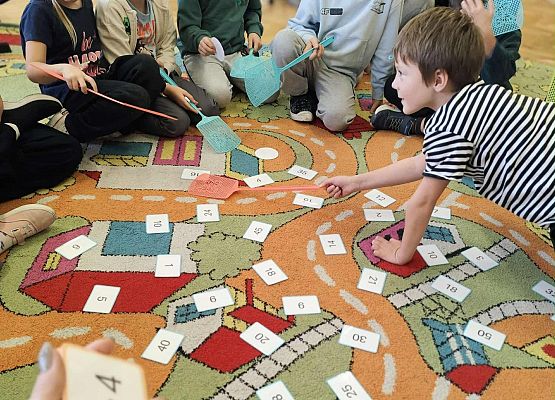 dzieci wykonując zadania bawią się na dywanie