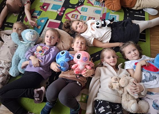 dzieci leżą i trzymają pluszowe misie