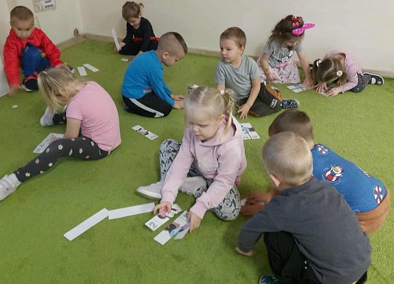 dzieci siedzą na dywanie i układają układanki