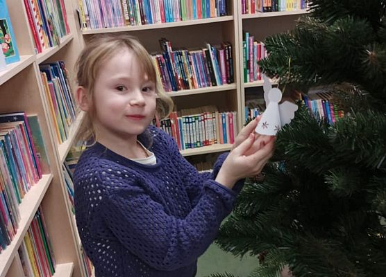 dziewczynka zawiesza na choince papierowego anioła