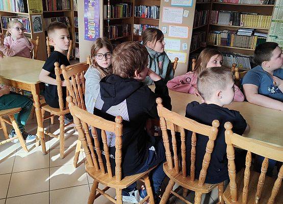 uczniowie siedzą przy stole podczas zajęć w biblioptece szkolnej