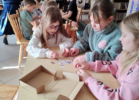 dzieci układają karty z dinozaurami