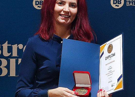 nauczycielka prezentuje otrzymany medal i dyplom