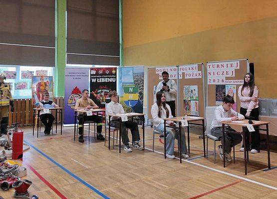 uczniowie siedzą przy stolikach i rozwiązują zadania