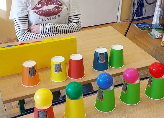 uczennica układa piłeczki na kubeczkach