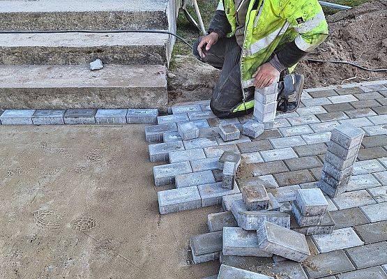 panowie pracują przy układaniu kostki brukowej przy budynku przedszkola