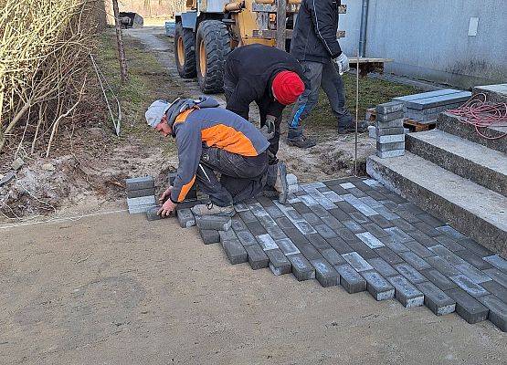 panowie pracują przy układaniu kostki brukowej przy budynku przedszkola