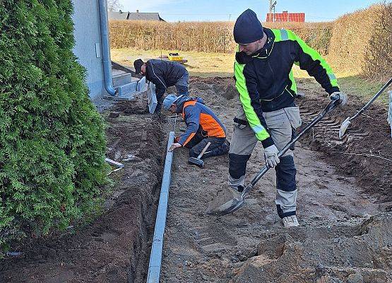 panowie pracują przy układaniu kostki brukowej przy budynku przedszkola