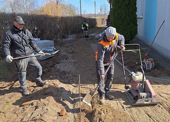 panowie pracują przy układaniu kostki brukowej przy budynku przedszkola
