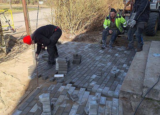 panowie pracują przy układaniu kostki brukowej przy budynku przedszkola