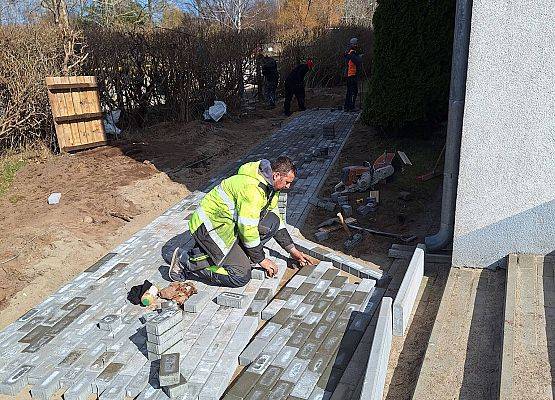 panowie pracują przy układaniu kostki brukowej przy budynku przedszkola