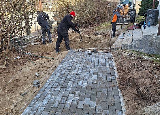 panowie pracują przy układaniu kostki brukowej przy budynku przedszkola