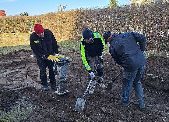 panowie pracują przy układaniu kostki brukowej przy budynku przedszkola