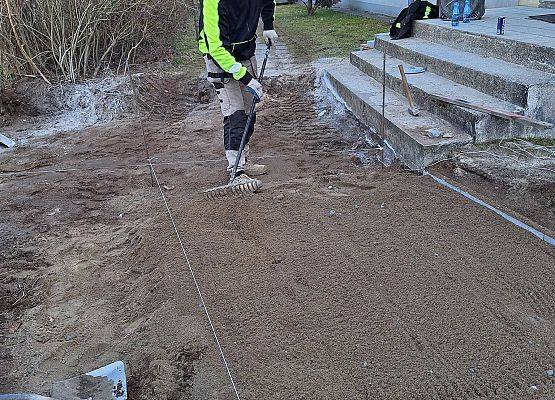 panowie pracują przy układaniu kostki brukowej przy budynku przedszkola
