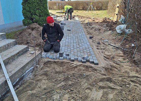 panowie pracują przy układaniu kostki brukowej przy budynku przedszkola