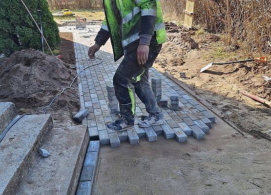 panowie pracują przy układaniu kostki brukowej przy budynku przedszkola