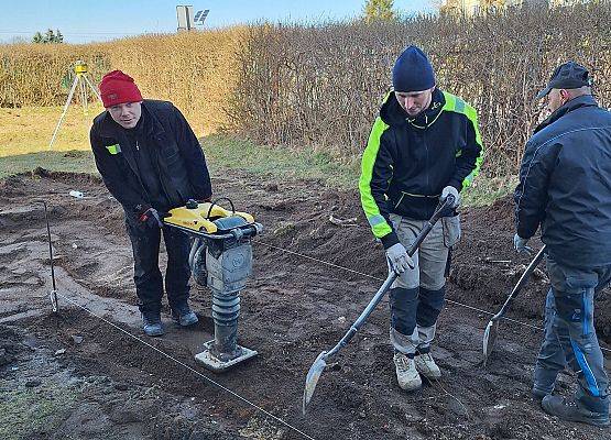 panowie pracują przy układaniu kostki brukowej przy budynku przedszkola