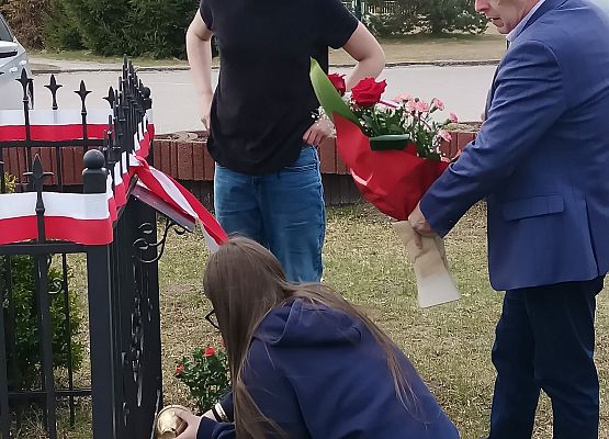 dyrektor składa wiązankę kwiatów przy Dębie Pamięci