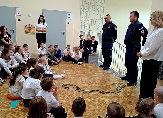 uczniowie siedzą podczas zajęć z policjantami
