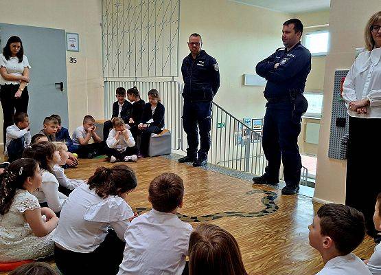 uczniowie siedzą podczas zajęć z policjantami