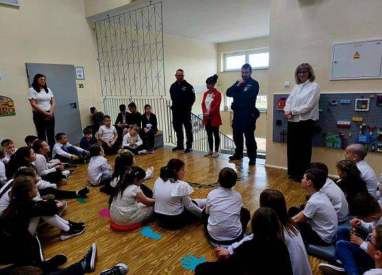 uczniowie siedzą podczas zajęć z policjantami