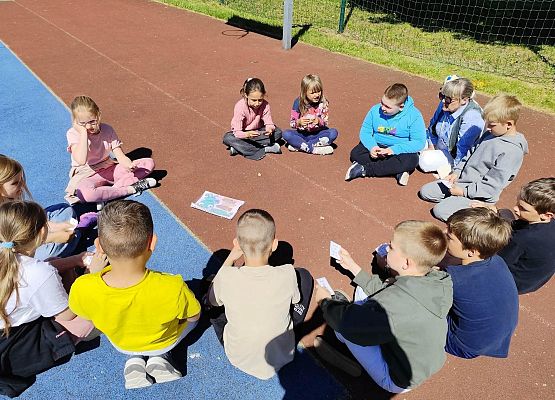 uczniowie z nauczycielką siedzą w kręgu